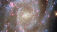 哈勃再秀宇宙美景：3500万光年外螺旋星系粉色星云“绽放”